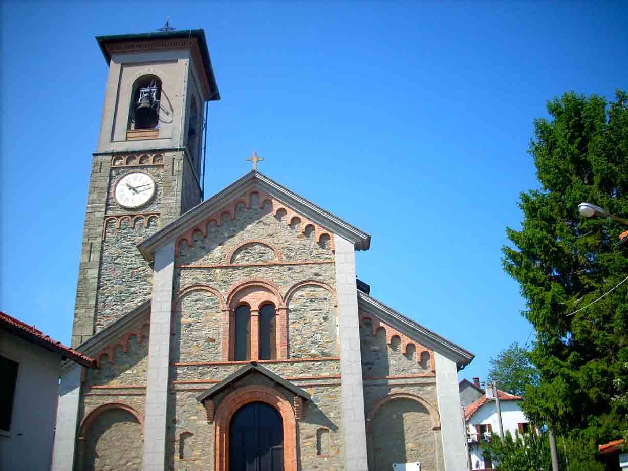 Chiesa in pietra e mattoni con campanile e orologio, cielo azzurro