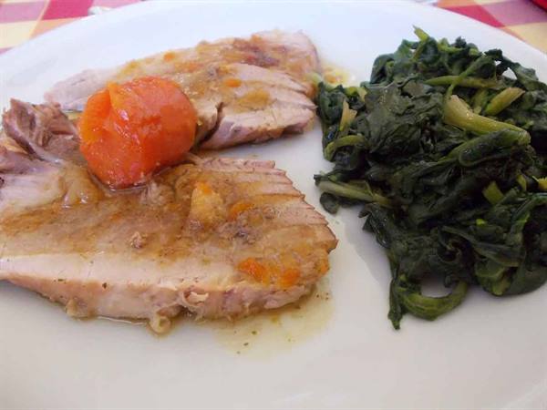Sliced meat with cherry tomatoes and spinach on a white plate