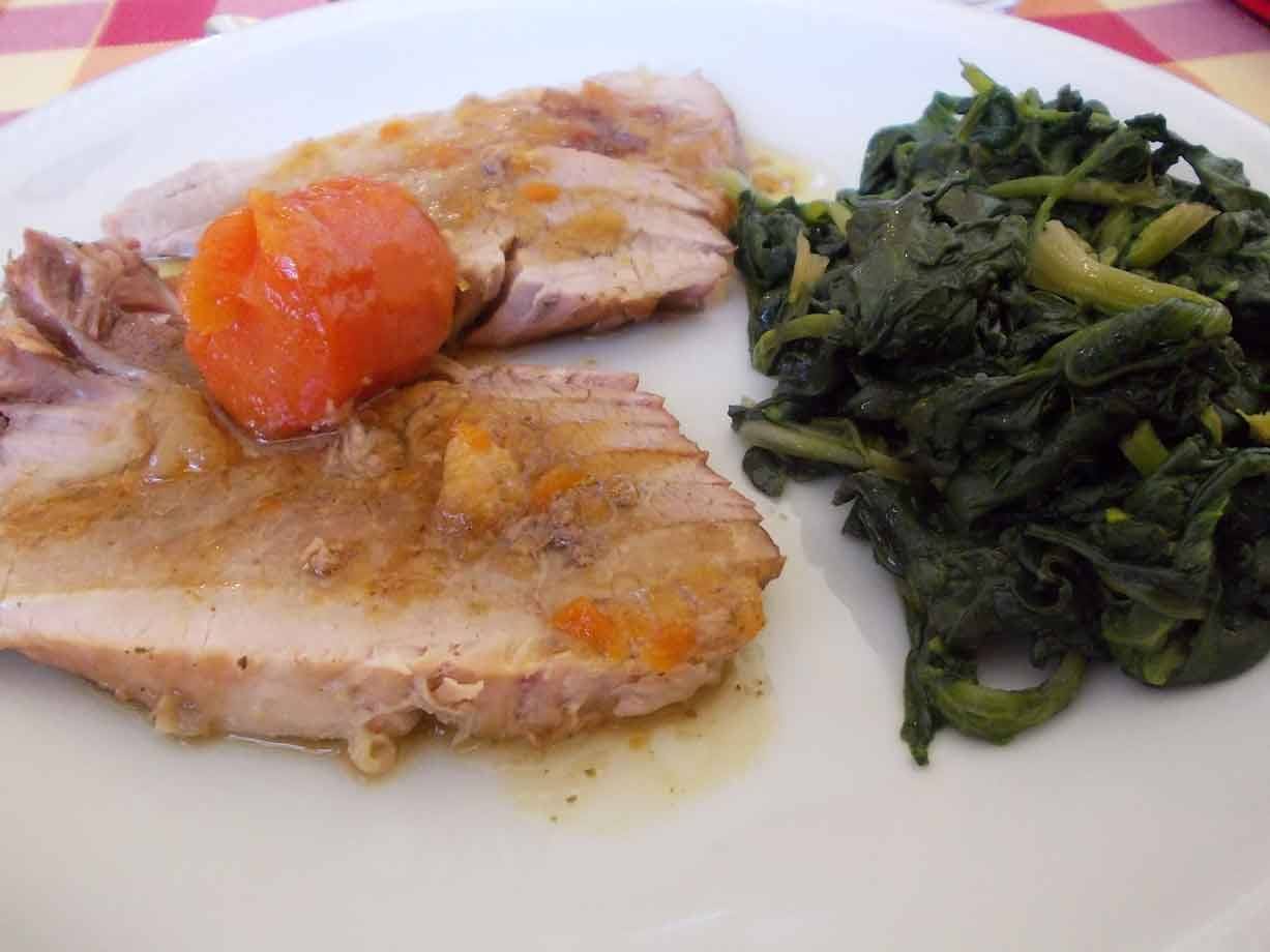 Fette di carne con pomodorini e spinaci al piatto bianco