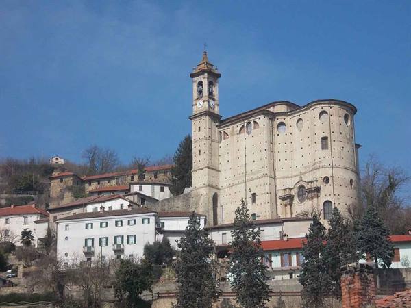 Stone bell tower and church rise above village houses under blue sky