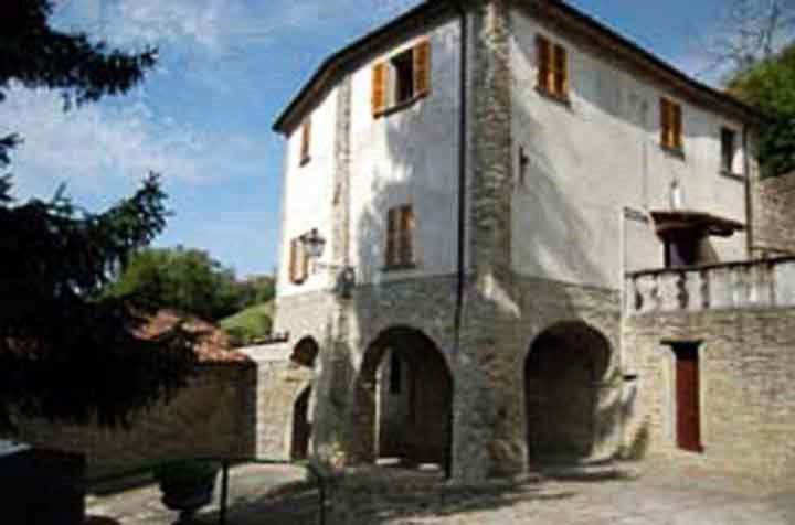 Casa in pietra e intonaco con arcate e serrande in legno al sole