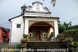 Small church with arched porch, red flowers and bell tower