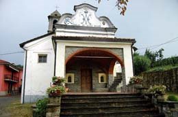 Chiesetta con portico ad arco, fiori rossi e campanile
