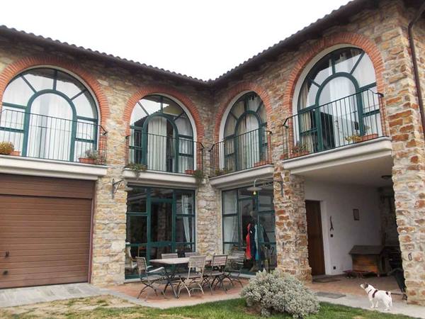Stone house with arched windows, garden table and a dog
