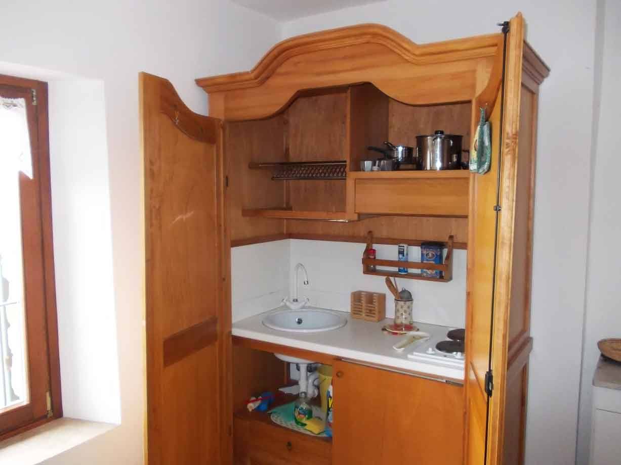 Angolo cottura in legno con lavello, fornelli e pentole, luce da finestra