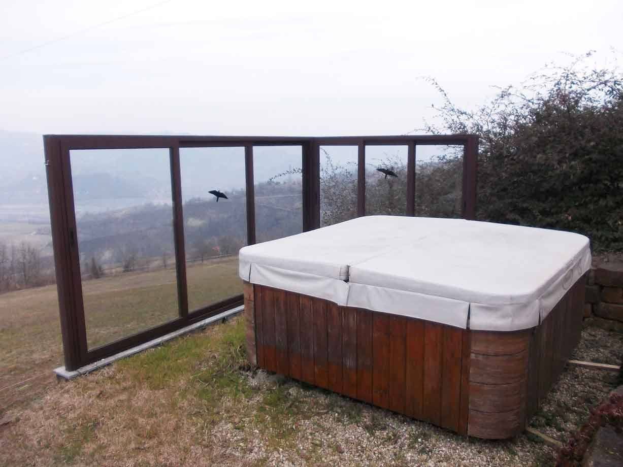 Vasca idromassaggio in legno coperta, su terrazza in erba con paravento in vetro