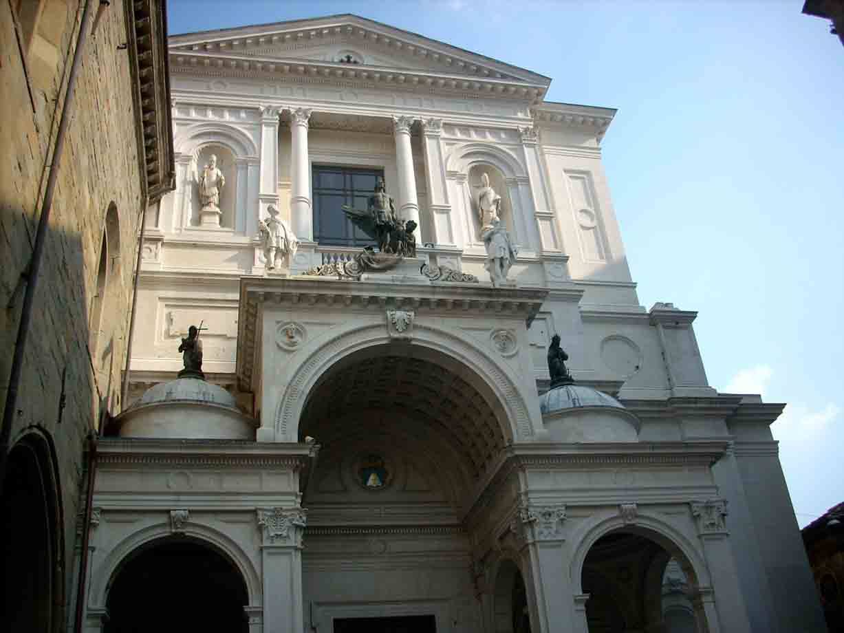 Facciata bianca barocca con statue di santi e cavaliere sulla balaustra