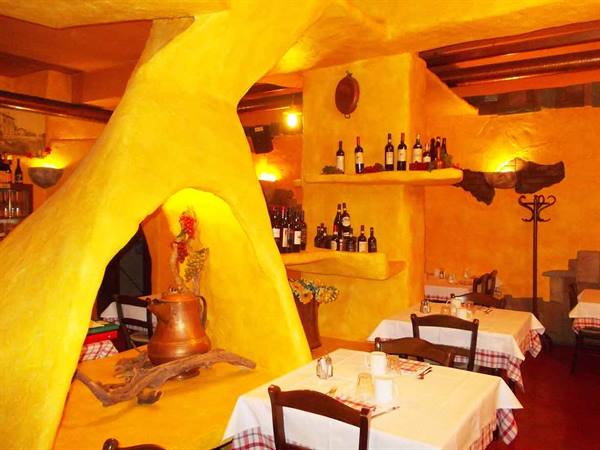 Restaurant interior with yellow plastered walls, wine bottles and set tables