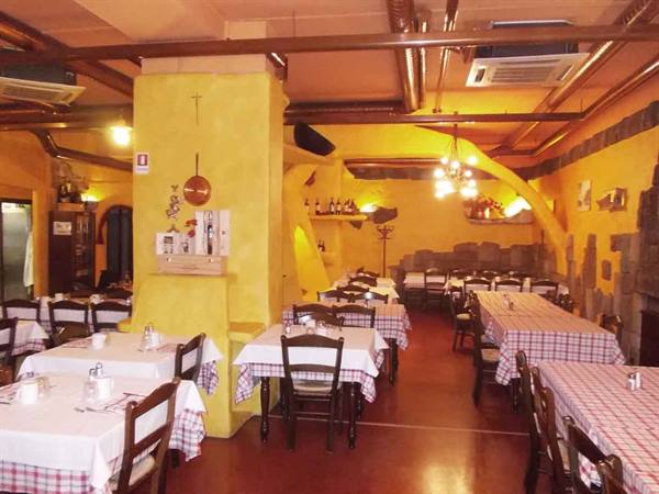 Trattoria dining room with set tables, yellow walls, wooden beams and chandelier