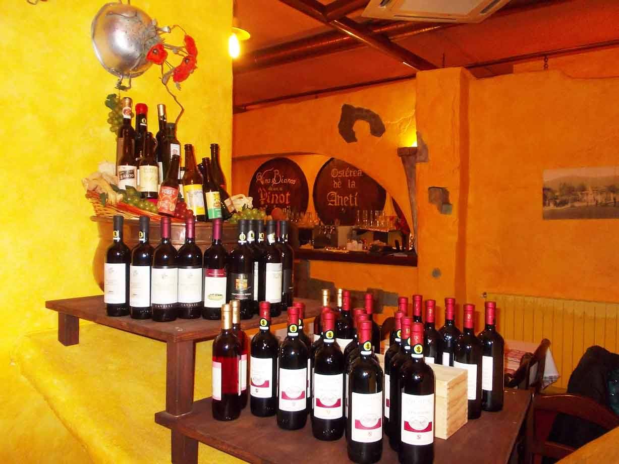 Bottiglie di vino rosso su tavoli di legno in una trattoria dalle pareti gialle
