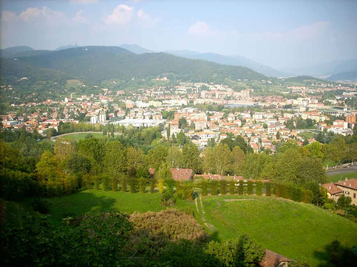 Città tra colline verdi viste dall'alto, tetti e case tra gli alberi