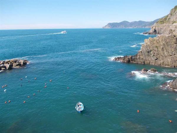 Blue boat on turquoise water among rocks and cliffs, Cinque Terre