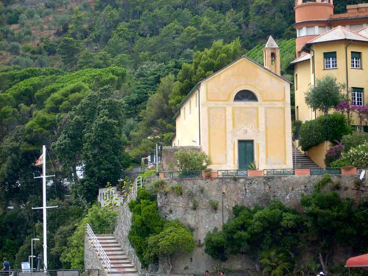 Chiesa gialla con campanile su scogliera verdeggiante, Portofino