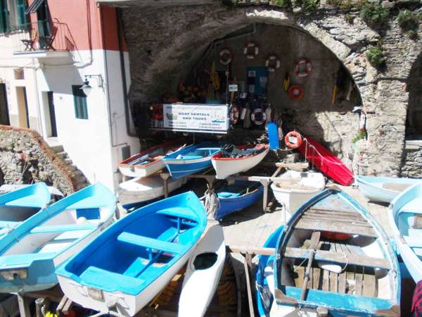 Blue wooden boats hauled up beneath the stone arch, Riomaggiore