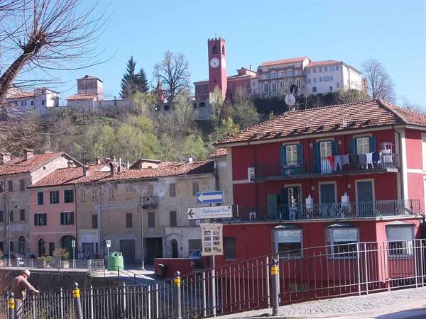 Piedmont village with colored houses, red clock bell tower and sunny hill