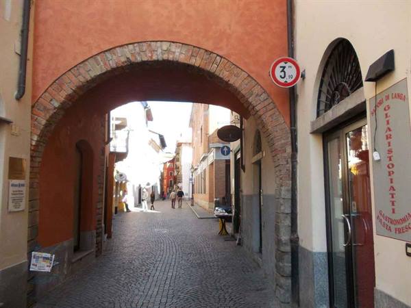 Brick arch over cobbled alley with pedestrians, Gagliardi deli sign