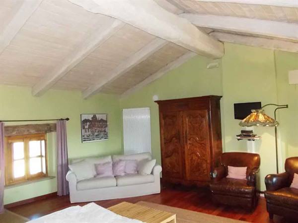 Living room with wooden beams, white sofa, antique wardrobe and leather armchairs