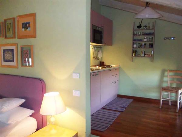 Purple bed beside green kitchenette lit by warm lamp
