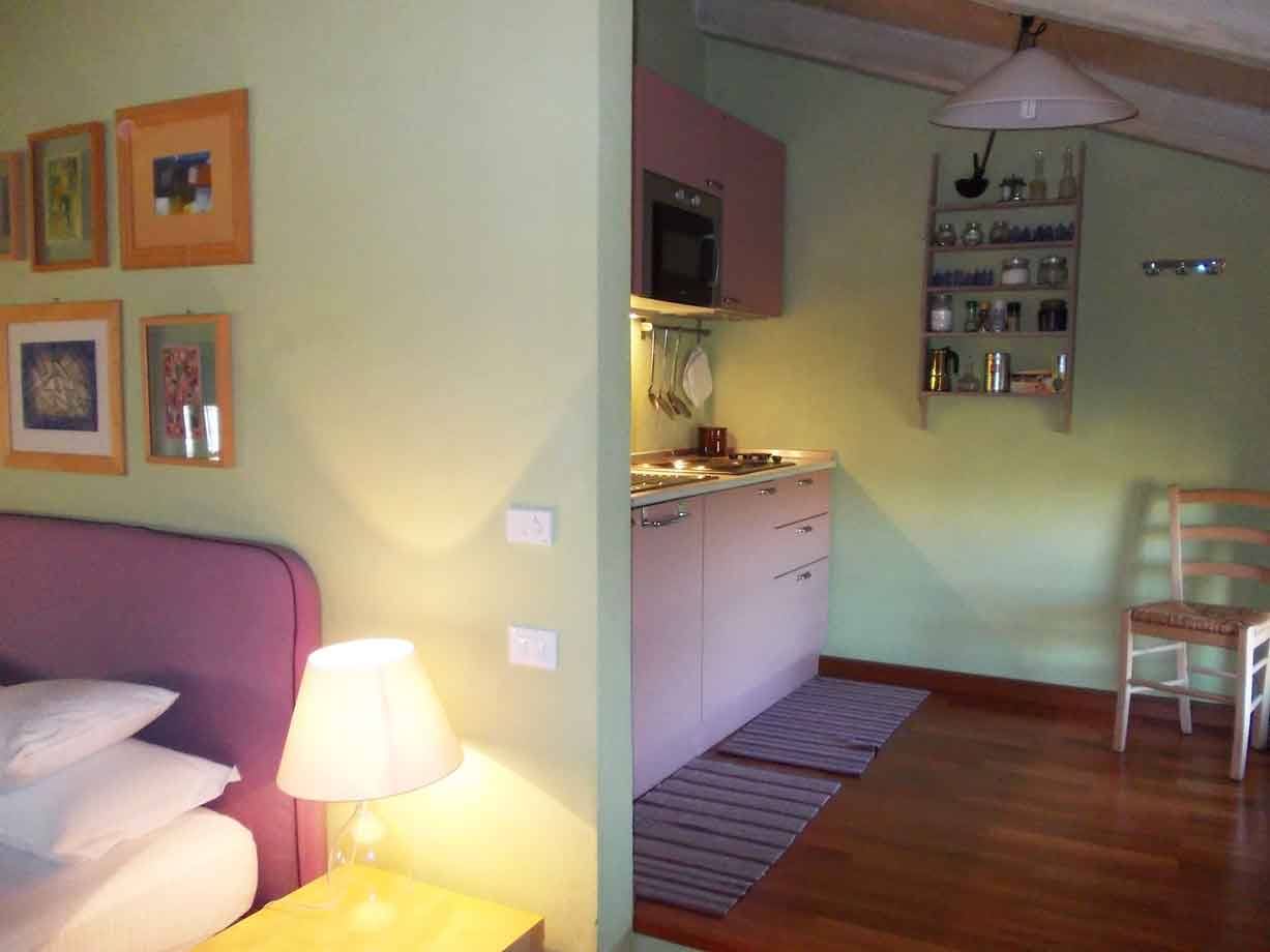 Camera con letto viola e angolo cottura verde acceso da lampada