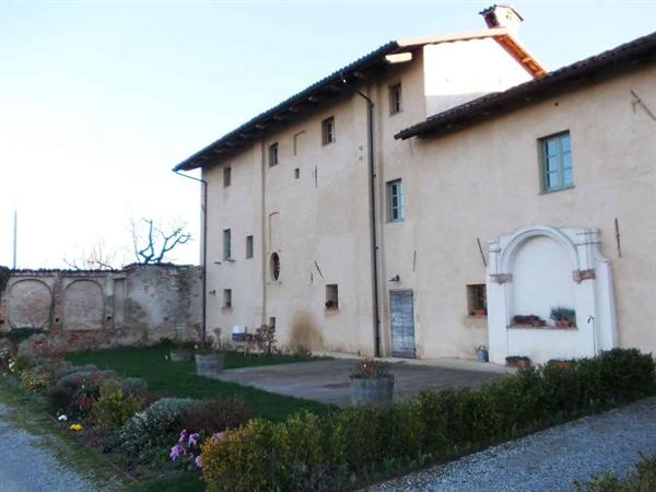 Old farmhouse with plastered facade, small shrine with flower pots and garden