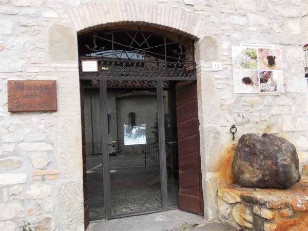 Olive oil museum entrance, wrought iron gate, stone wall, ancient millstone