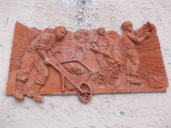 Terracotta bas-relief showing bricklayers with wheelbarrow and hammer at work