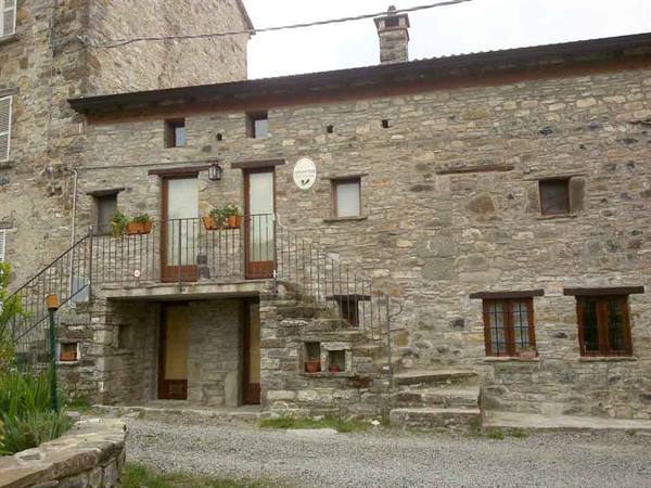 Grey stone farmhouse with external staircase and wrought iron railing