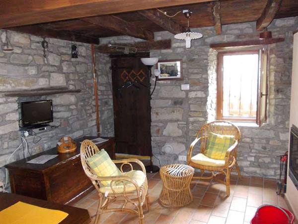 Rustic living room with stone walls, wicker chairs and wooden beams