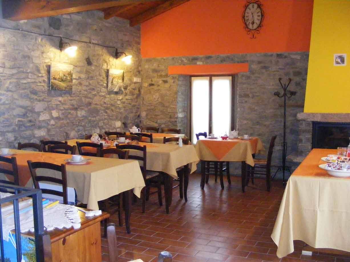 Sala da colazione in pietra con tavoli apparecchiati e tovaglie gialle