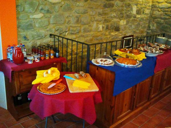 Cakes and juices on red and blue clothed tables, stone wall
