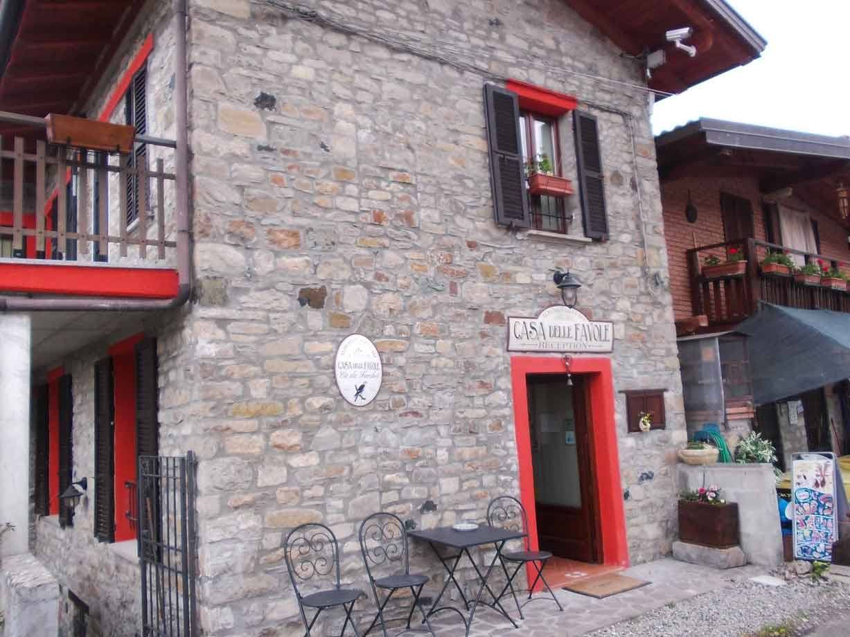 Casa del Parco, edificio in pietra con insegna e tavolini in ferro davanti all'ingresso