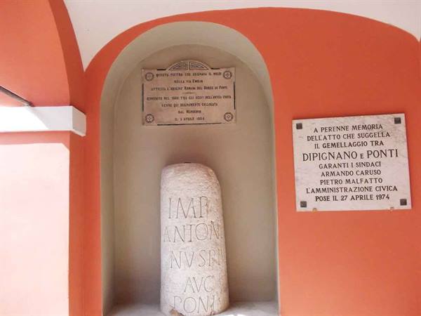 Roman stone milestone with inscription set in orange niche with marble plaques