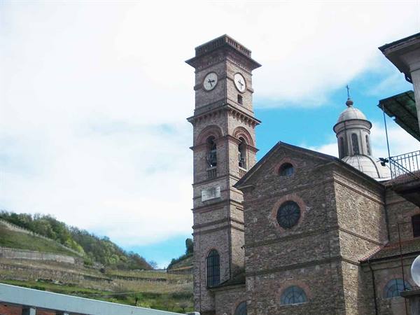 Stone bell tower with clock beside the church, cultivated hills in the background
