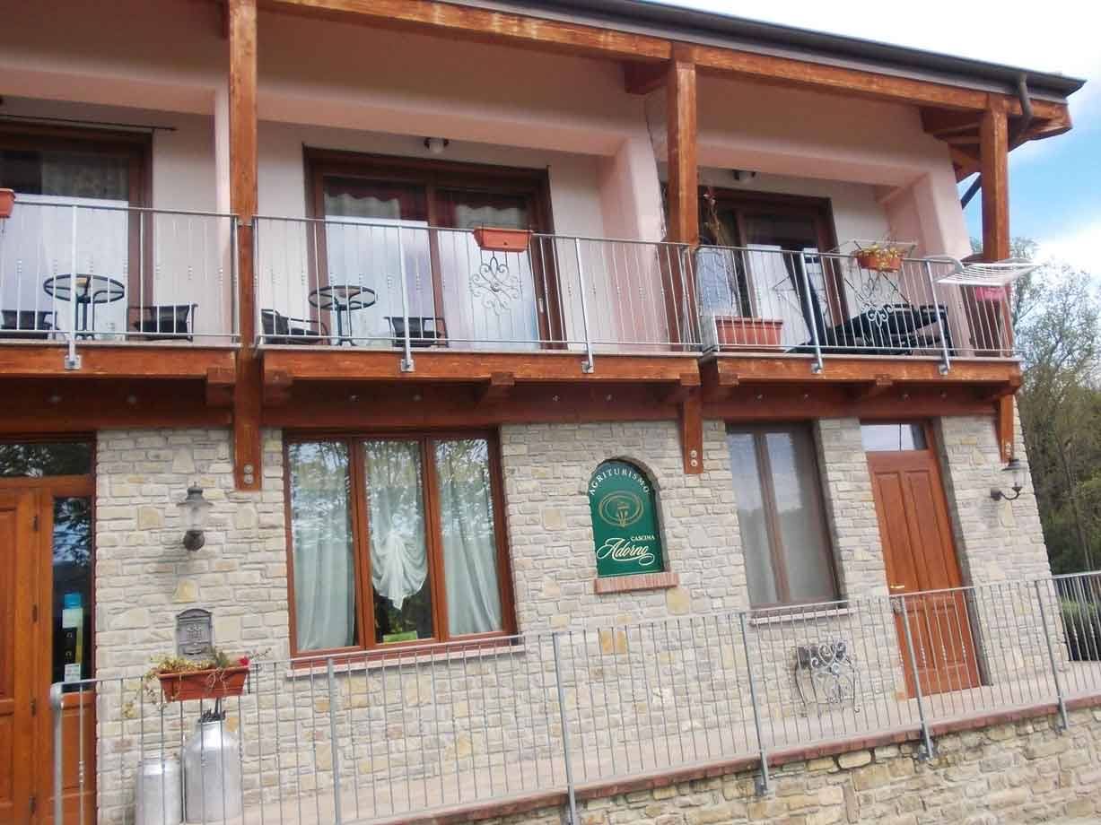Agriturismo in pietra con balconi lignei e insegna verde