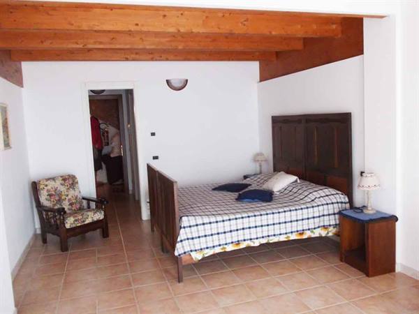 Bedroom with wooden bed, exposed ceiling beams and floral armchair