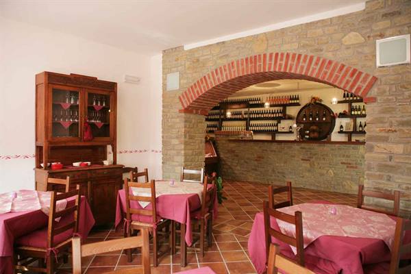 Trattoria dining room with pink tablecloths, stone wall, brick arch and bottle bar