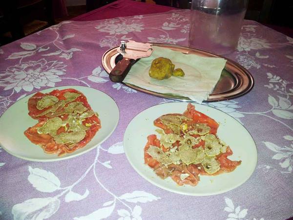 Beef carpaccio with truffle shavings, metal tray and slicer on lilac tablecloth