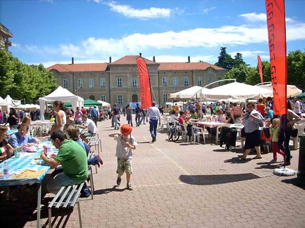 Child in red helmet runs between tables at town square festival