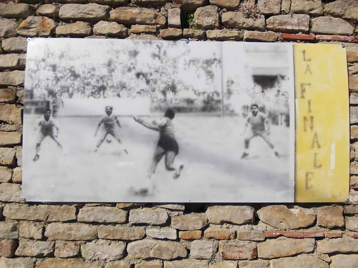 Targa su muro di pietra con foto in bianco e nero di calciatori, scritta La Finale
