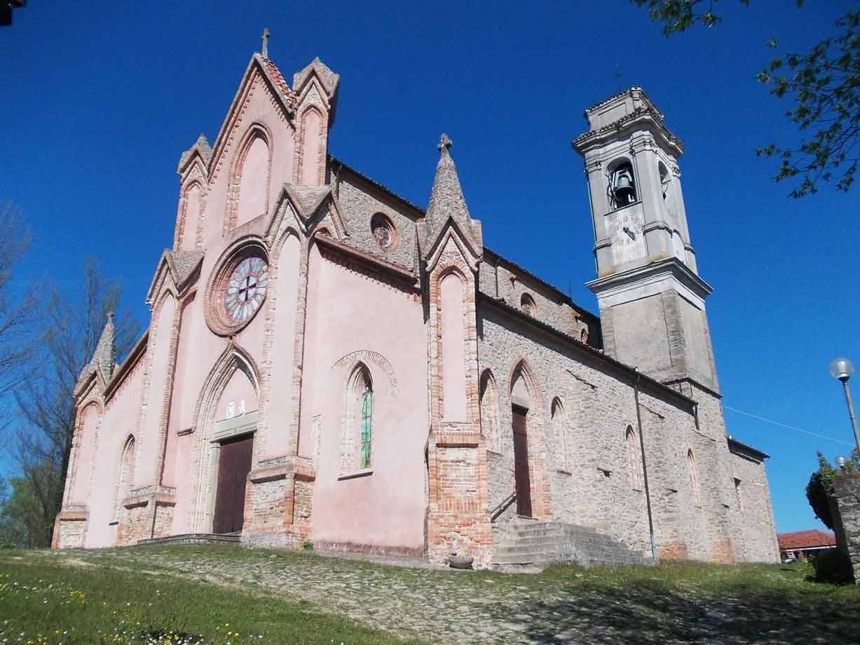 Chiesa gotica in pietra e mattoni con rosone e campanile sotto cielo azzurro