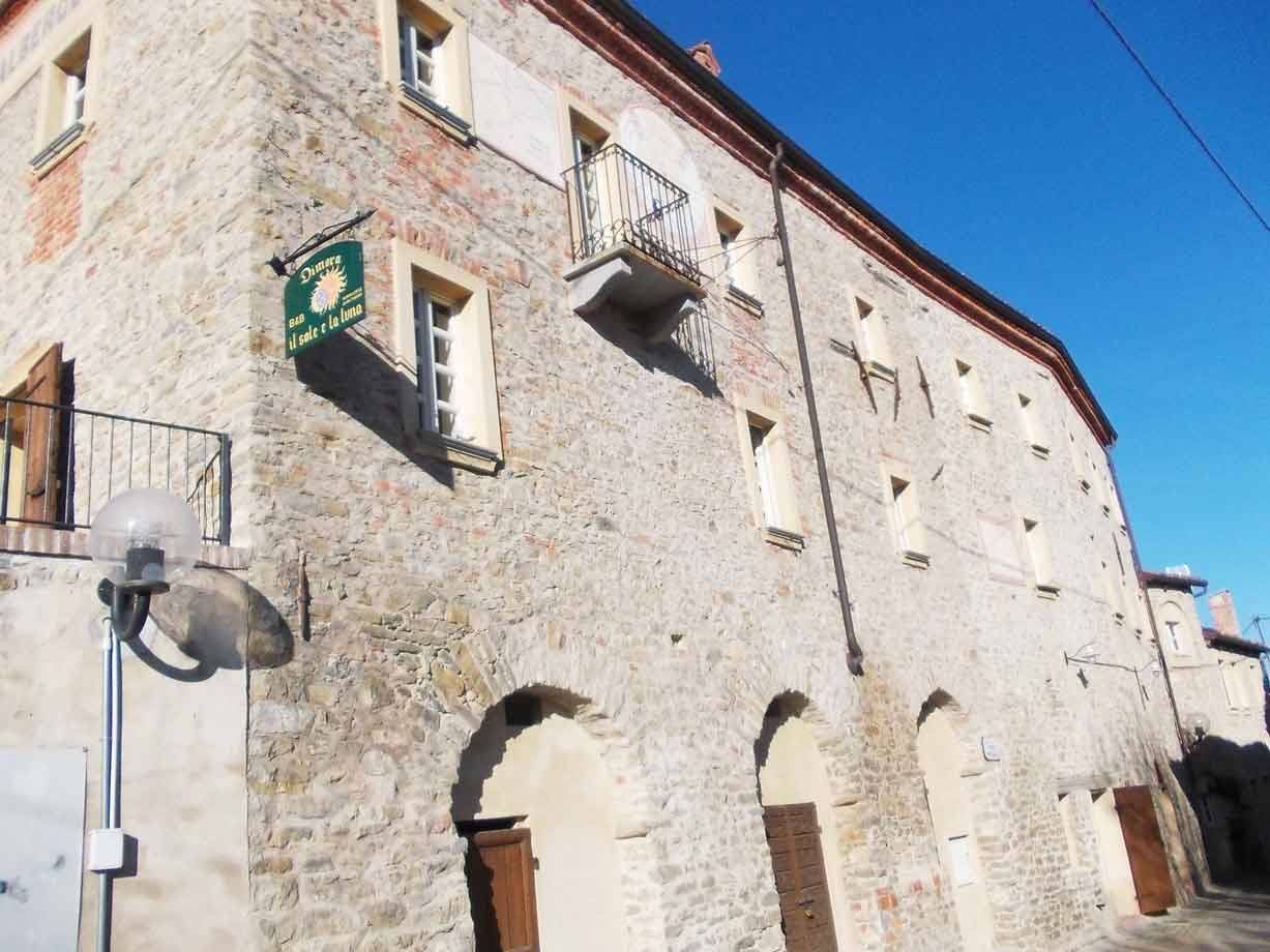 Antico edificio in pietra con portici ad arco e insegna verde, cielo azzurro