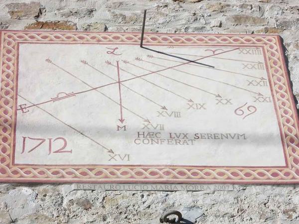 Painted sundial dated 1712 on a stone wall, with Latin inscriptions