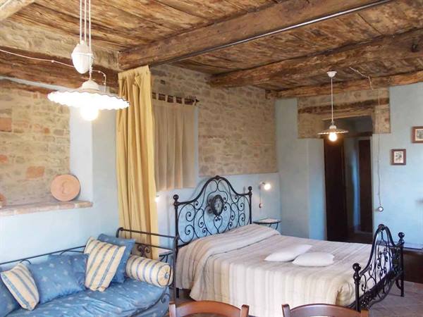 Rustic bedroom with wrought iron bed, wooden beams and stone walls