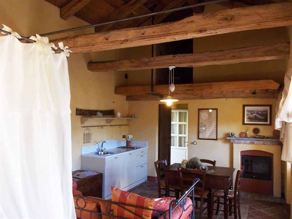 Rustic interior with wooden beams, kitchen corner, wooden table and fireplace