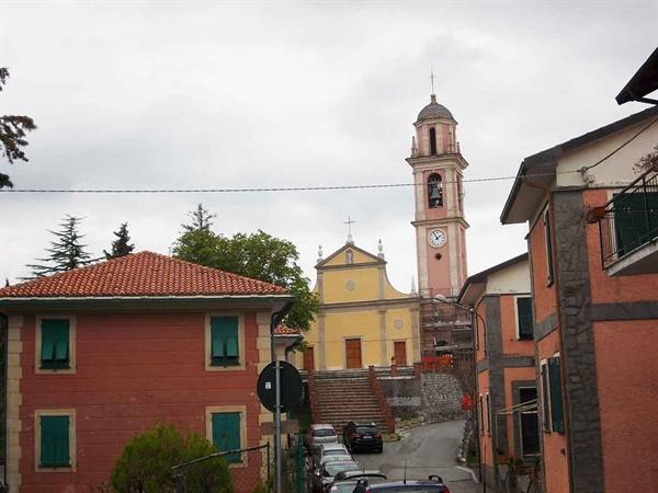 Yellow church with bell tower and clock above the village's red houses