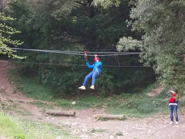Boy in blue jacket ziplining through the trees