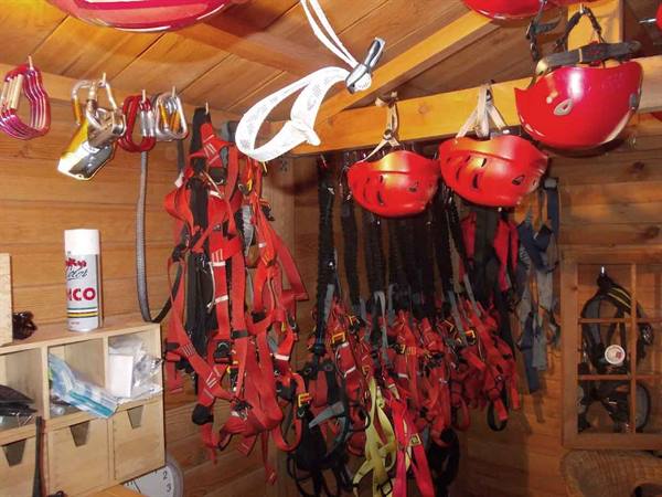 Red helmets and climbing harnesses hanging in a wooden equipment hut