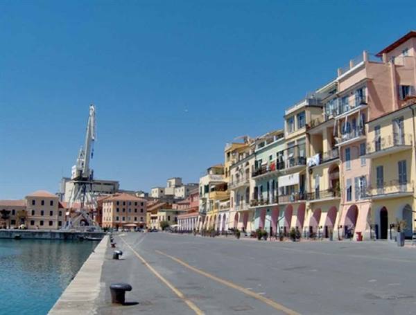 Savona waterfront with port crane and colorful arcaded buildings under blue sky