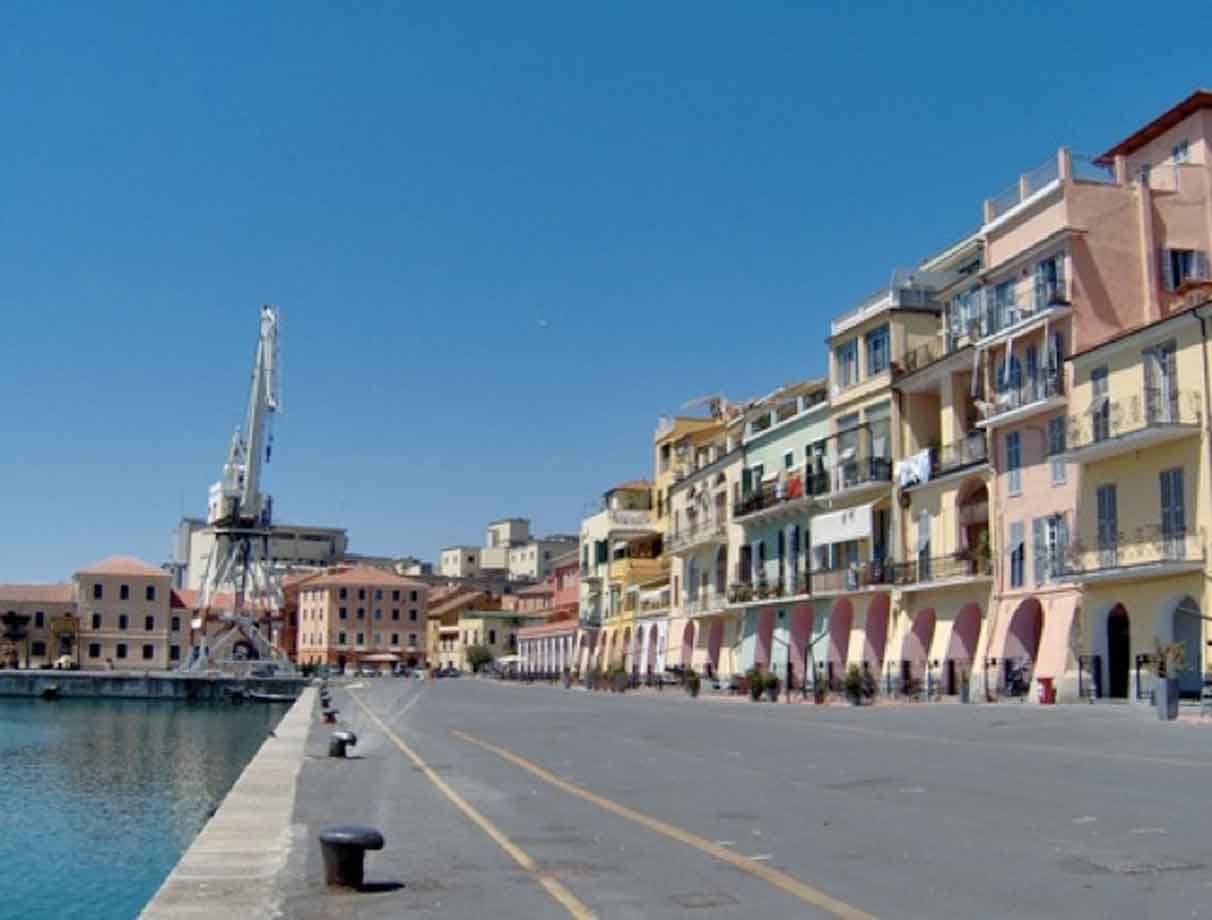 Lungo molo di Savona con gru portuale, case colorate sotto cielo azzurro