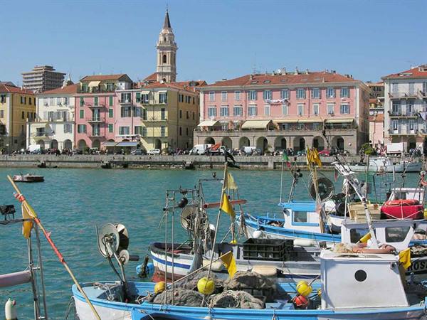 Blue fishing boats moored in the harbor before colorful buildings and bell tower